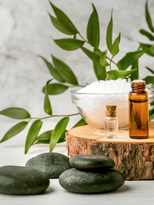 beauty treatment items for spa procedures on white wooden table. massage stones, essential oils and sea salt. copy space